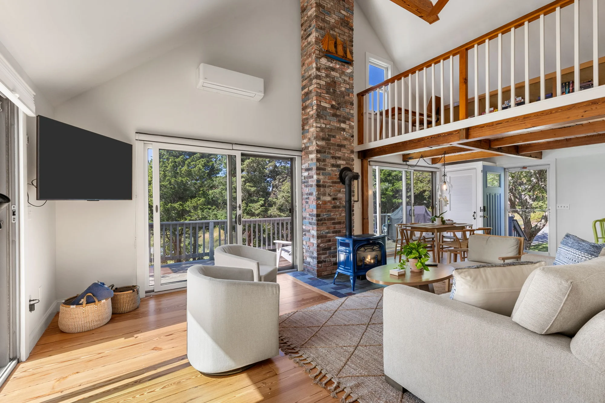 Bright living room with exposed wood beams, loft and comfortable coastal furnishings